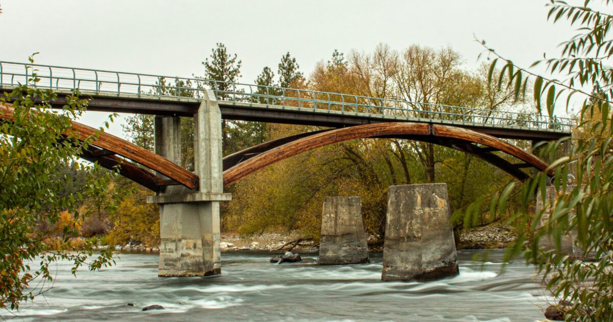 A bridge surrounded by trees spans the Spokane River.