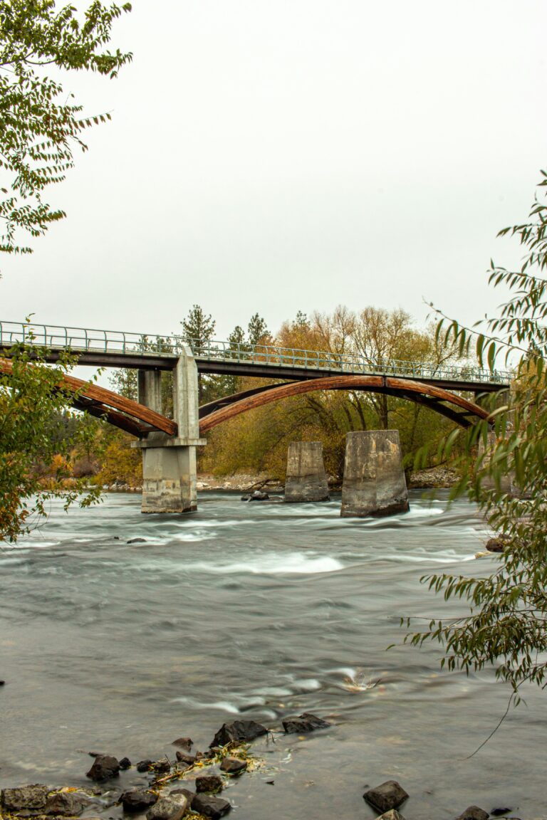 A bridge surrounded by trees spans the Spokane River.