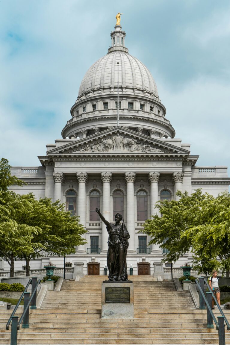 Bronze statue of a woman in front of a white building.