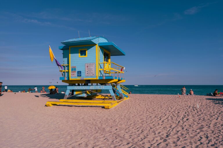 A blue-and-yellow lifeguard tower sits on the beach with the ocean in the background