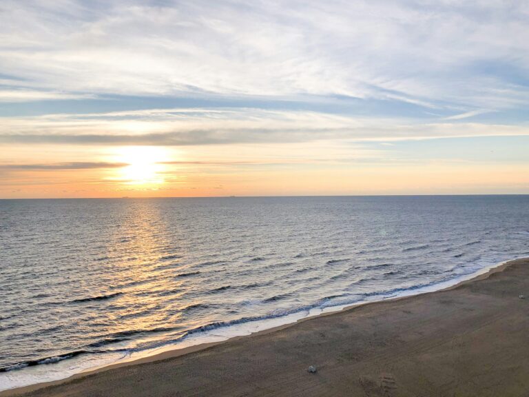 The sun sinks on the horizon as waves crash into the sand at Virginia Beach.