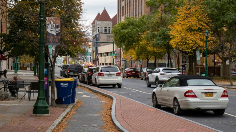 Brick sidewalks by a picturesque street in Syracuse, NY, with cars parked nearby