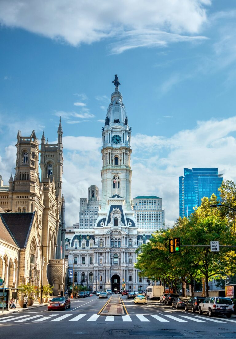 Philadelphia City Hall stands tall under a blue sky, with its iconic clock tower topped by a statue of William Penn