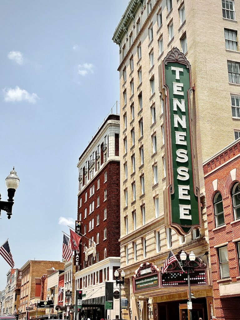 A theater with a large Tennessee sign on a city street with American flags on the buildings.