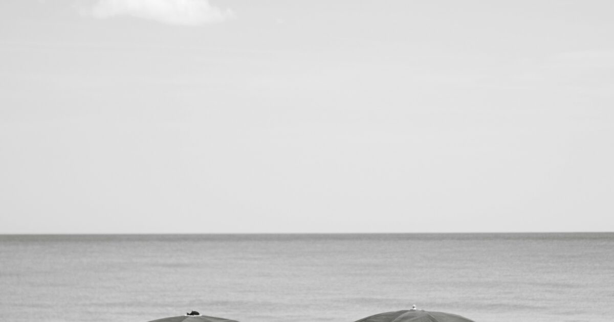 Black and white photo of chairs and umbrellas on a sunny beach