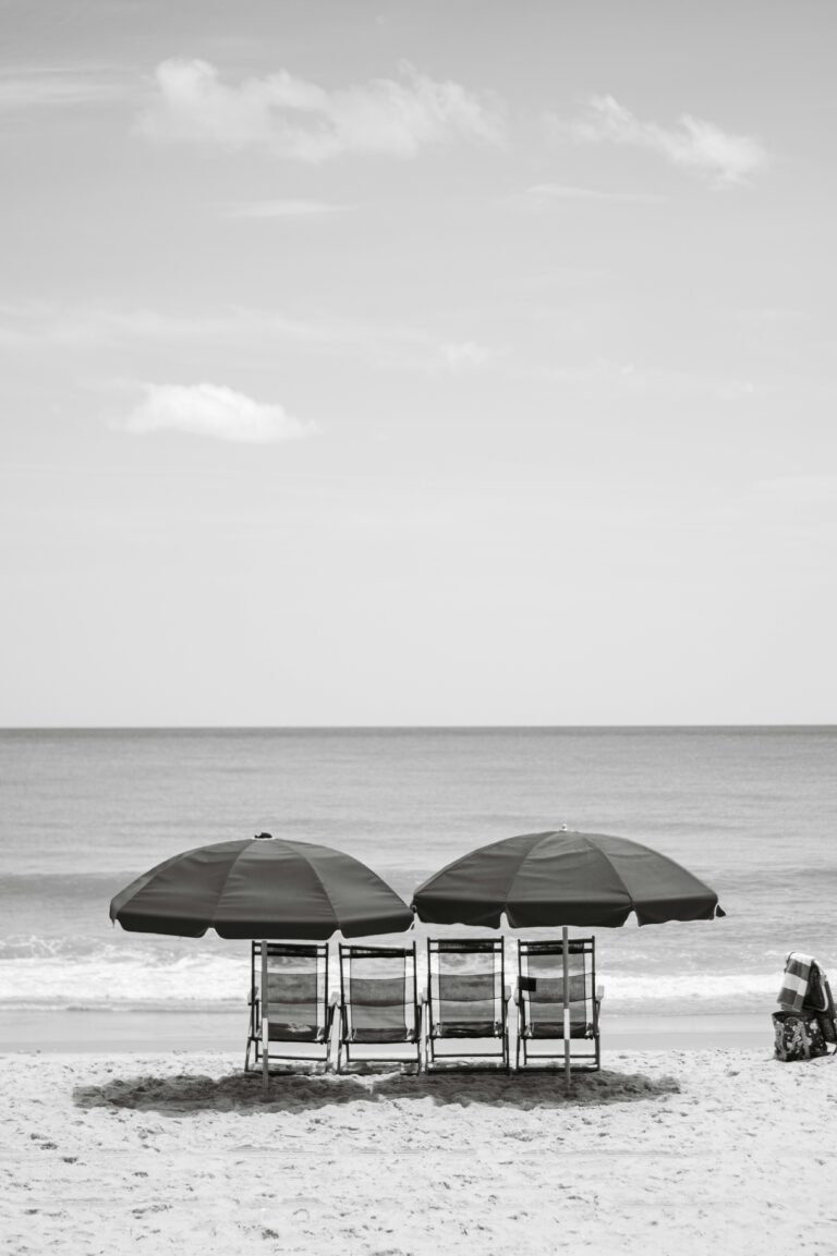 Black and white photo of chairs and umbrellas on a sunny beach