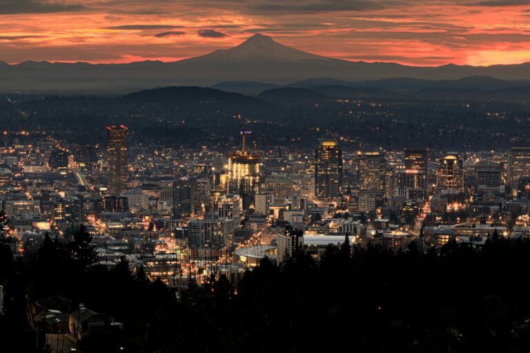 Downtown Portland lit up at sunset with mountains in the background