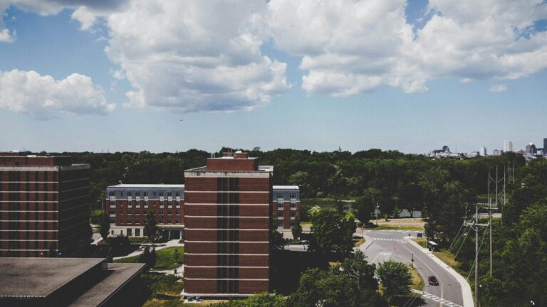 Lush green trees surround brick buildings in Rochester, NY