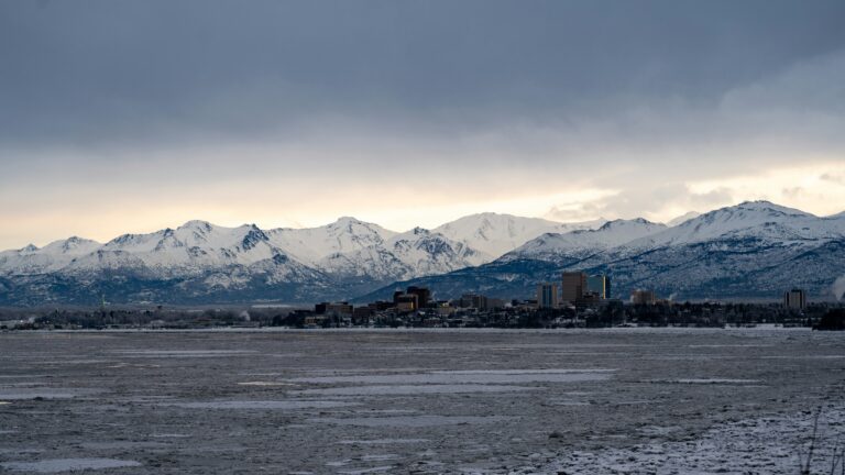 A landscape view of the Anchorage city skyline with snow-covered mountains in the background.