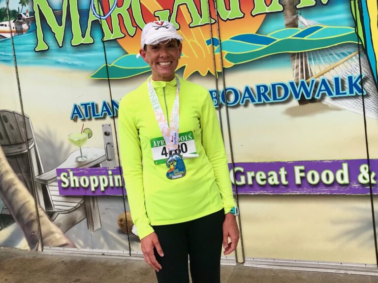 woman in marathon race gear standing in front of a sign