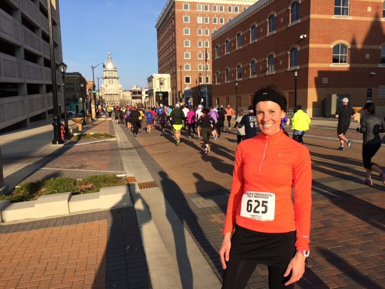 woman in marathon race gear standing in street with other racers behind her