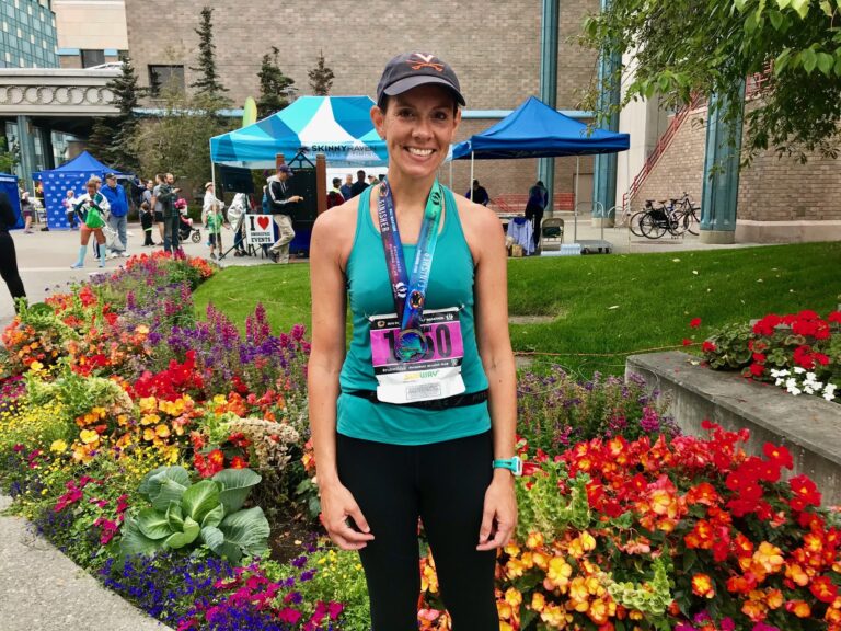 woman in marathon gear standing in front of colorful flowers