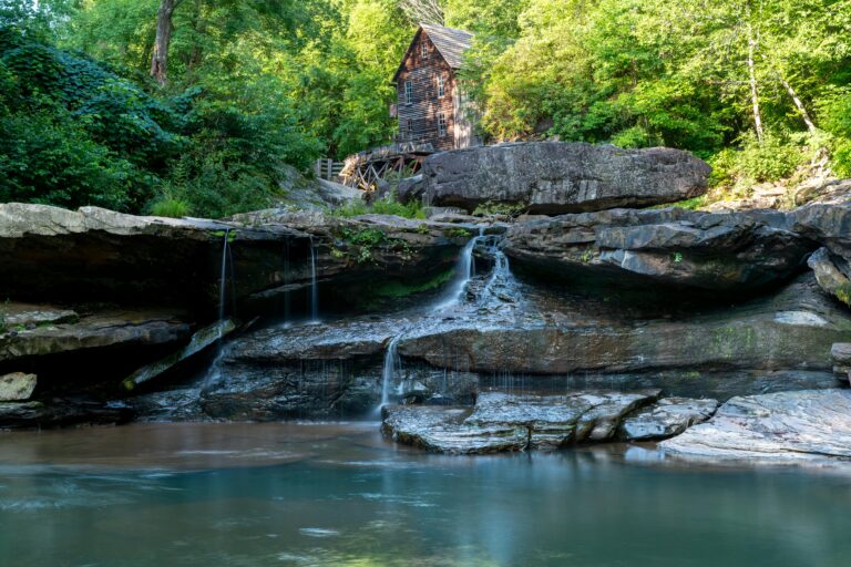 Scenic view of a vintage wooden grist mill and cascading falls along the river.