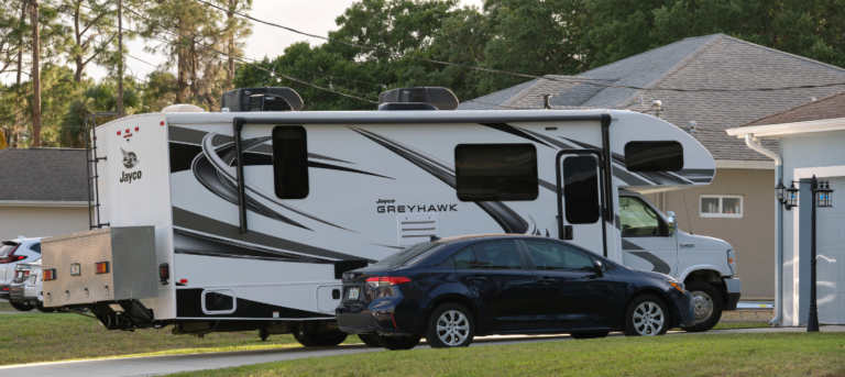 Motorhome parked in a residential driveway next to a car