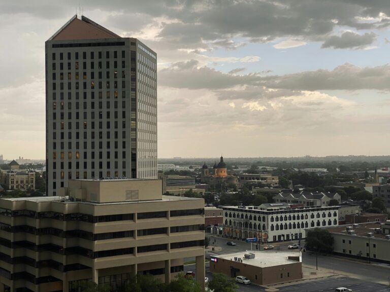 Wichita skyscraper, parking garage, and a church in the distance, under a cloudy sky