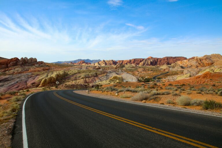 A road winds through a colorful desert landscape in the Valley of Fire, Nevada with mountains in the background