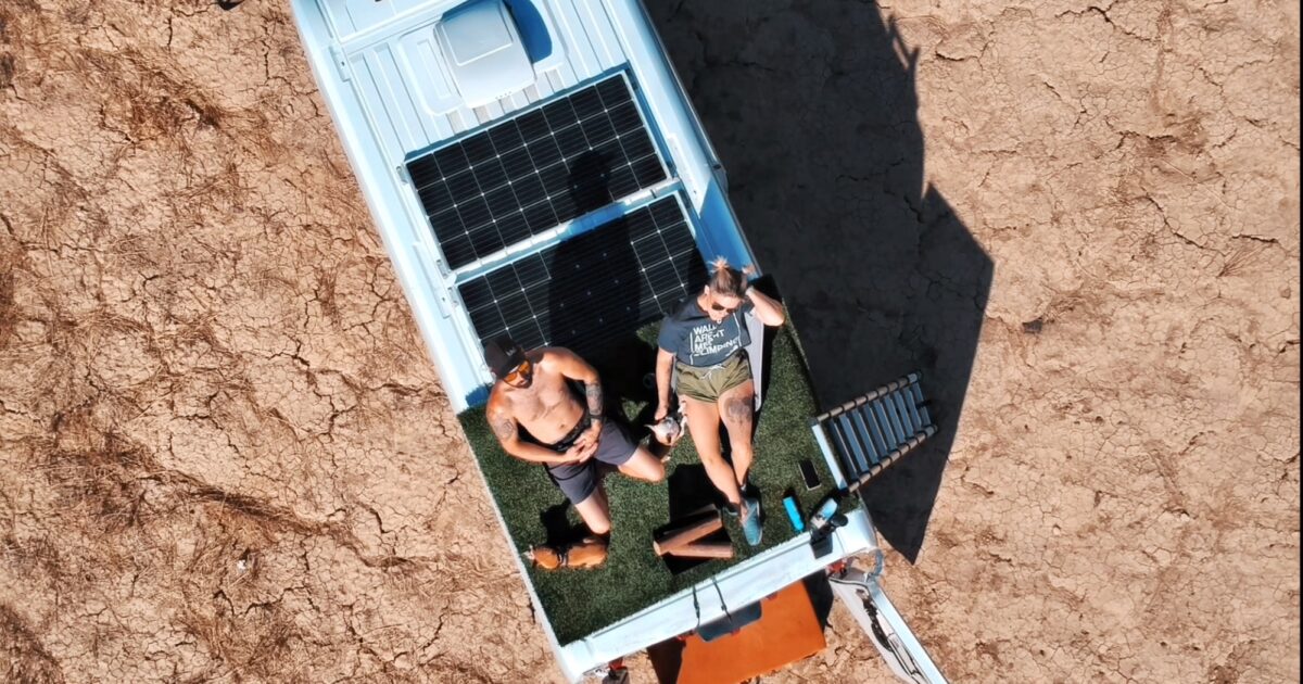 couple on the roof of a van with solar pannels and a portable power station goal zero