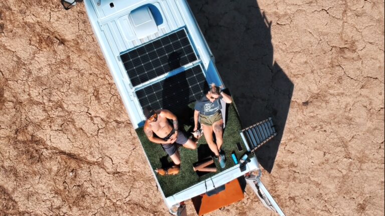 couple on the roof of a van with solar pannels and a portable power station goal zero