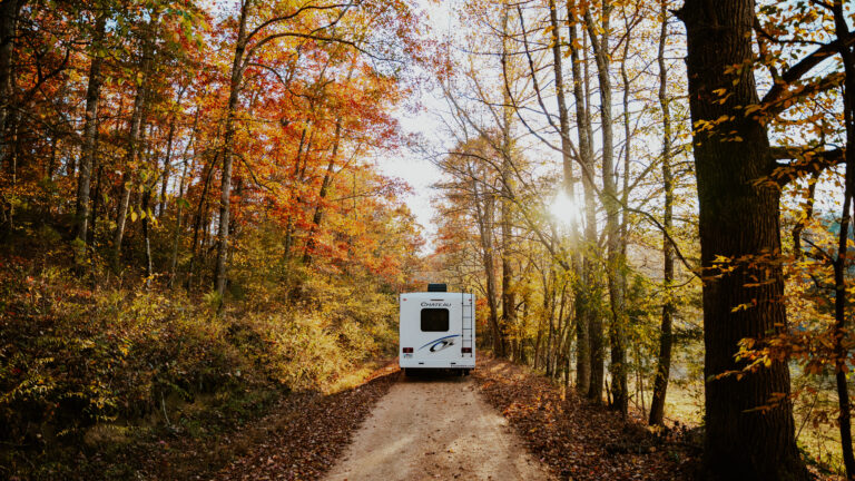 an RV driving through beautiful fall foliage