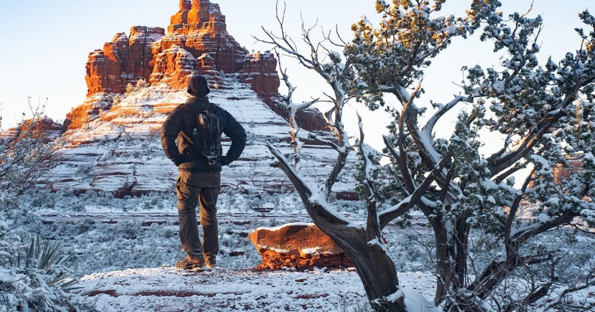 A man hikes along snowy red rocks in Sedona, Arizona, a great holiday travel destination by RV