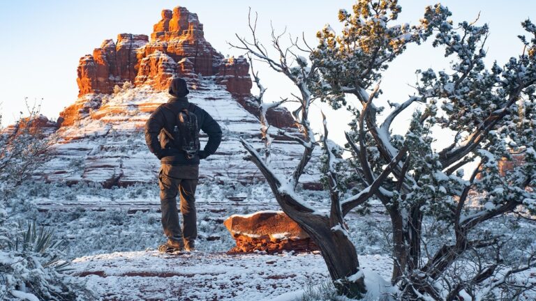 A man hikes along snowy red rocks in Sedona, Arizona, a great holiday travel destination by RV