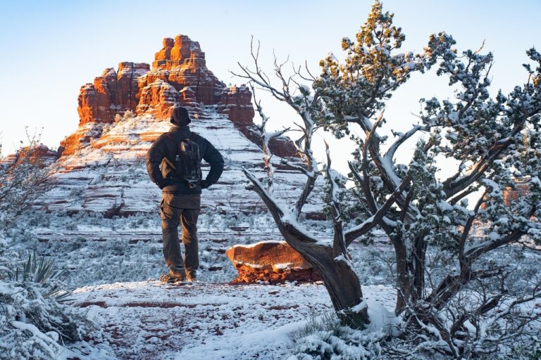 A man hikes along snowy red rocks in Sedona, Arizona, a great holiday travel destination by RV