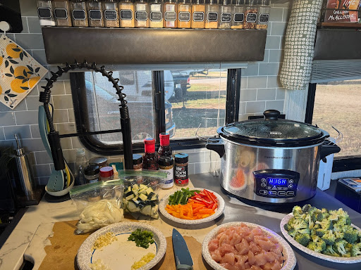 Food prepping fresh food like veggies and meat while dinner cooks in crock pot in an RV,