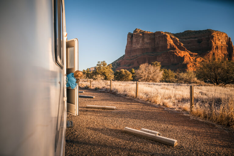 young boy peeking out of an rv and looking at a red rock formation