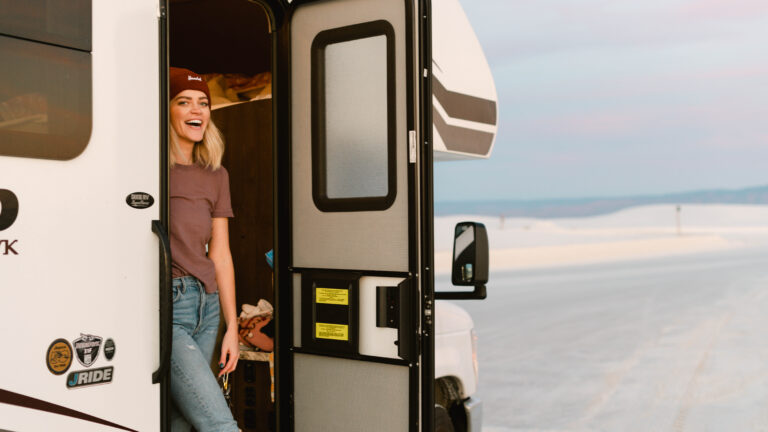 A woman stands in the door of her Class C RV rental