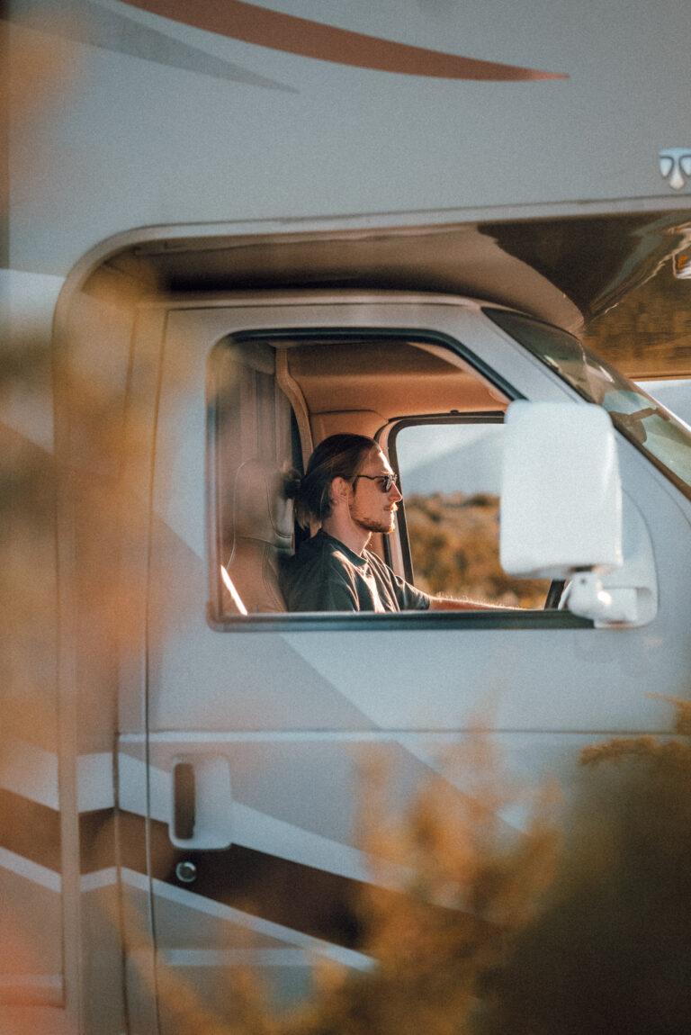 A man sits in the driver's seat of a Class C RV