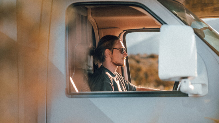 A man sits in the driver's seat of a Class C RV