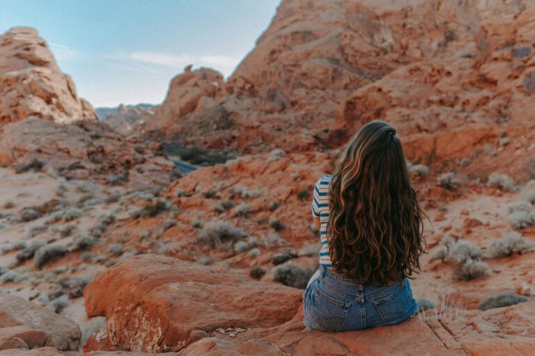 A woman sits overlooking the red rocks of Valley of Fire State Park in Nevada