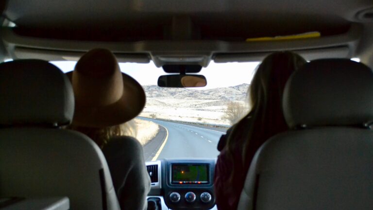 Two people gaze out of an RV windshield at a desert landscape, where RV HVAC is useful
