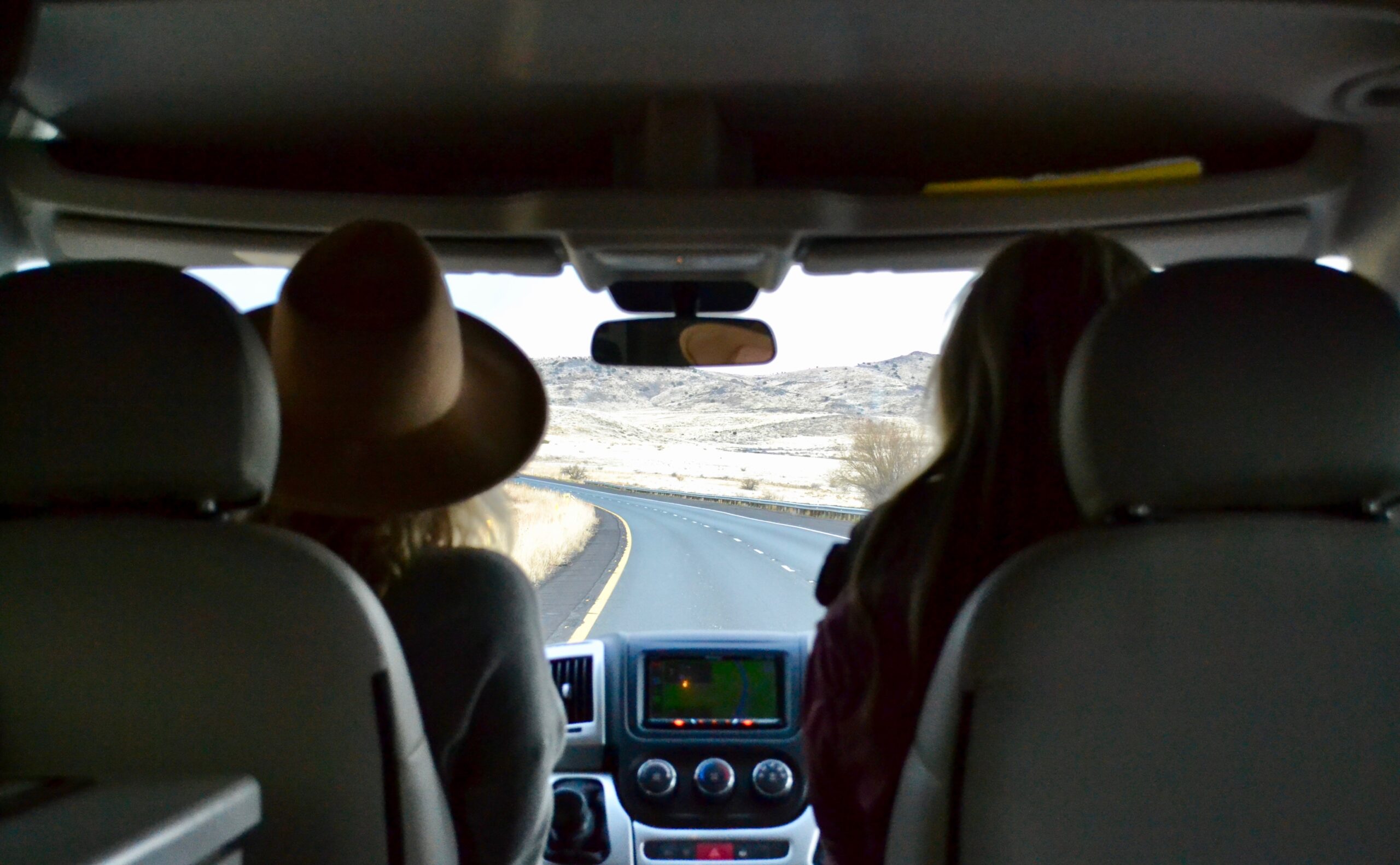 Two people gaze out of an RV windshield at a desert landscape, where RV HVAC is useful