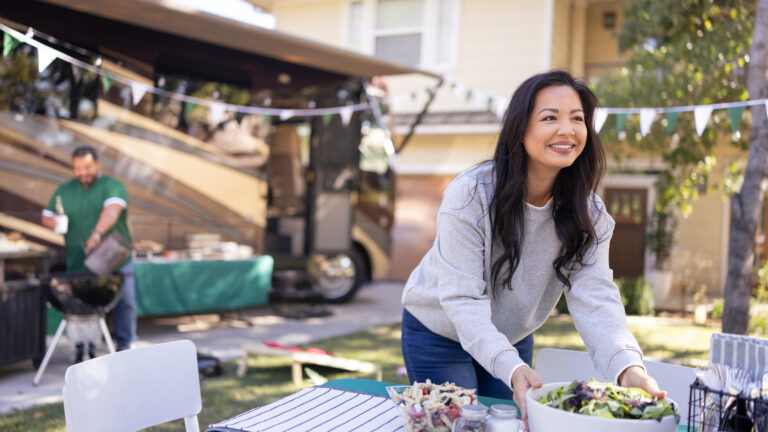 A woman sets out a meal in front of an RV decorated for the holidays