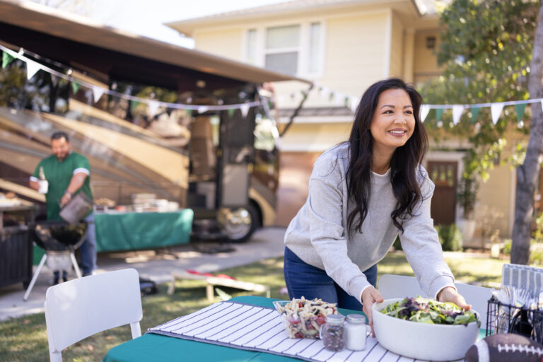 A woman sets out a meal in front of an RV decorated for the holidays