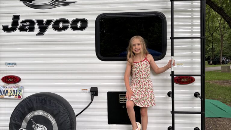little girl standing on the back of a jayco travel trailer