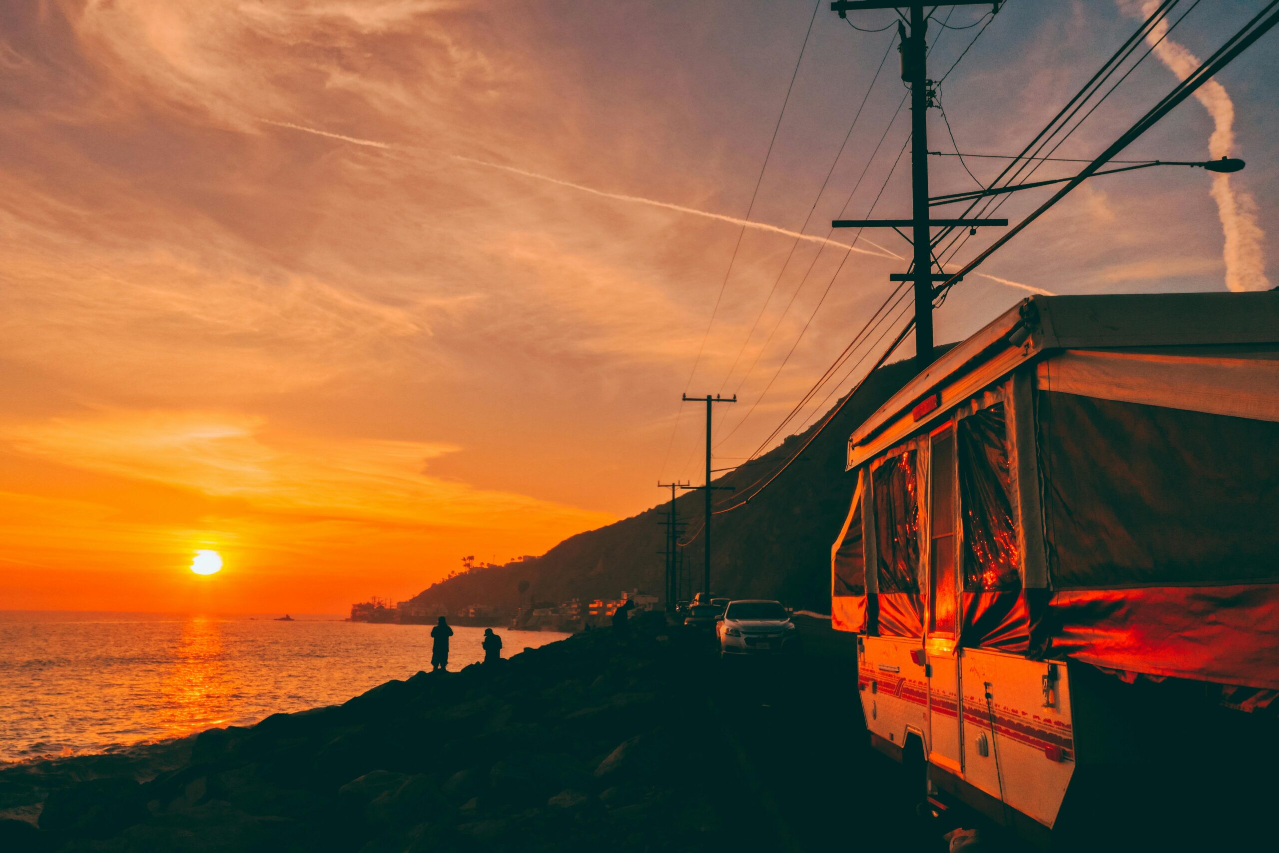 A pop-up trailer along a waterfront with a setting sun