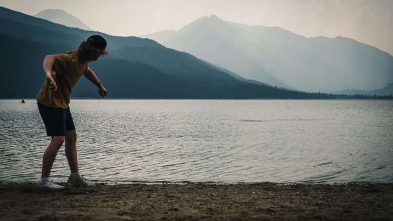 A man skips a stone into Wallowa Lake in Oregon, one of the best lakes for an RV vacation
