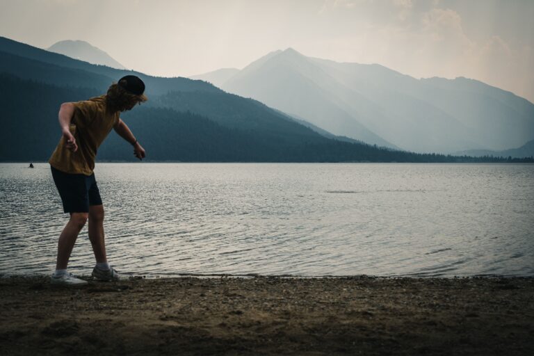 A man skips a stone into Wallowa Lake in Oregon, one of the best lakes for an RV vacation