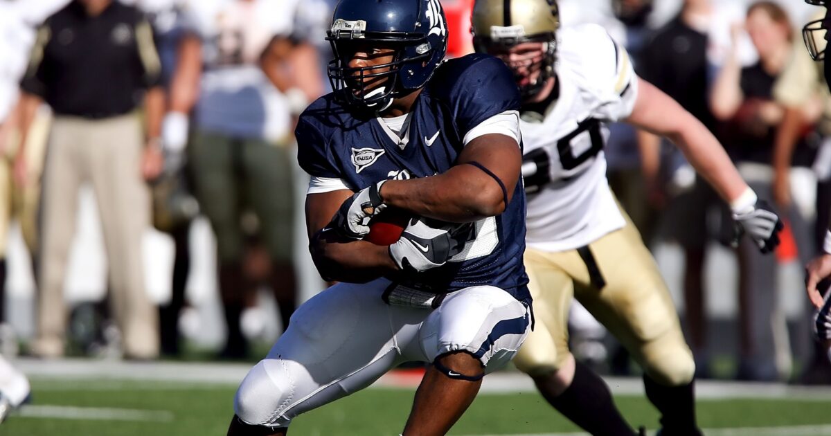 College football players run with the ball