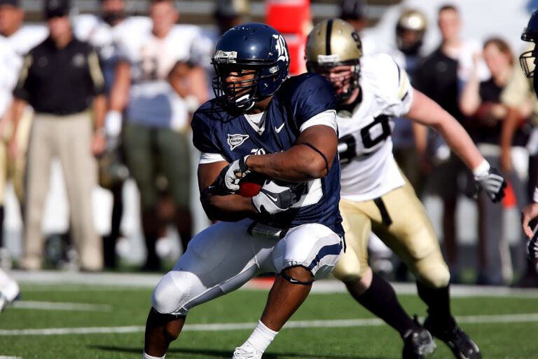 College football players run with the ball