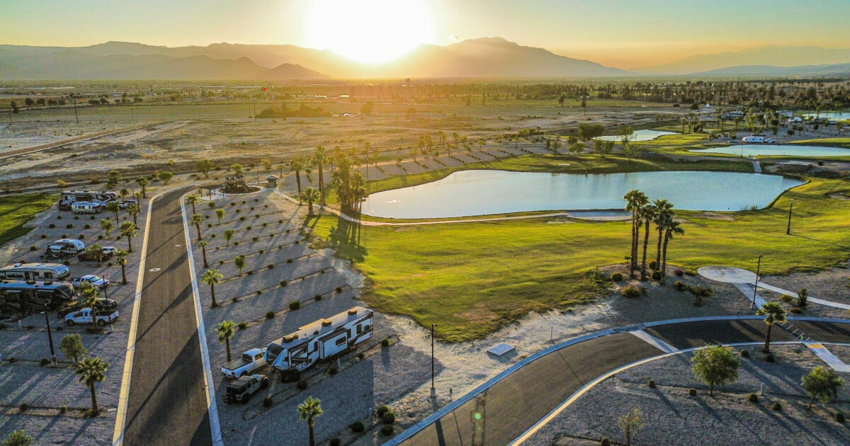 coachella lakes rv resport: view of an rv parked near a pond with mountains in the distance