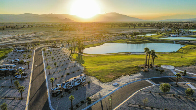 coachella lakes rv resport: view of an rv parked near a pond with mountains in the distance